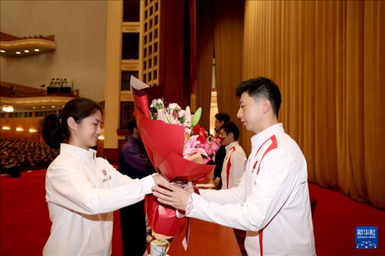 11月15日，一名學(xué)生代表在報(bào)告會(huì)上向乒乓球運(yùn)動(dòng)員馬龍（右）獻(xiàn)花。新華社記者 李明 攝