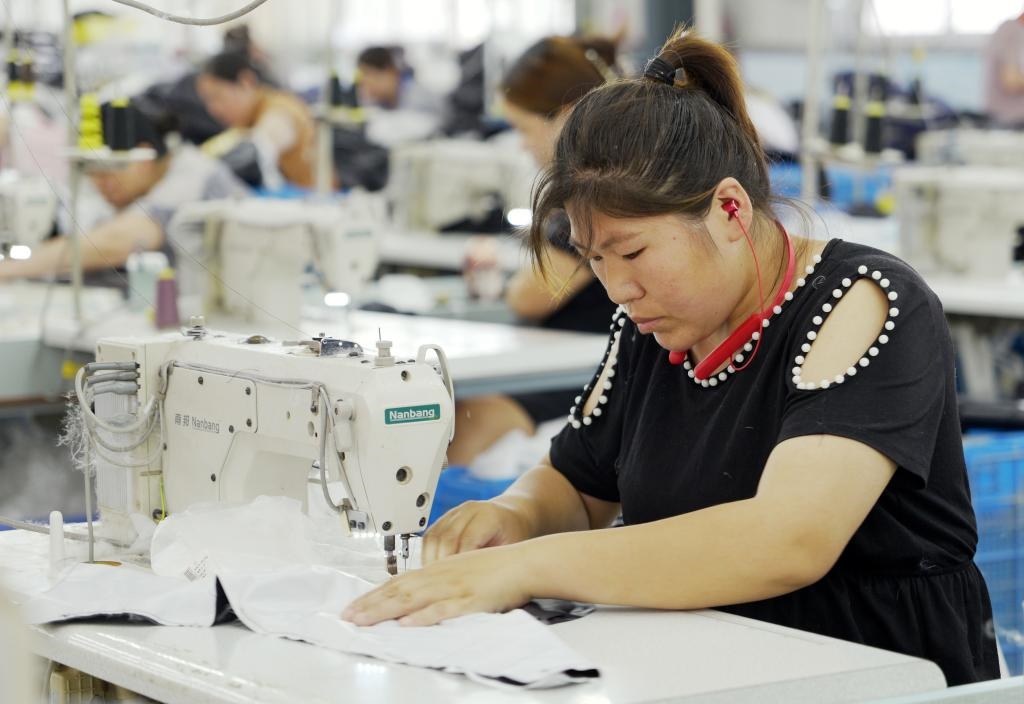 5月20日，村民在李寨村服裝加工廠內(nèi)忙碌。河南省周口市沈丘縣馮營(yíng)鎮(zhèn)李寨村地處豫東平原。近年來，乘著脫貧攻堅(jiān)與鄉(xiāng)村振興政策的東風(fēng)，李寨村積極探索產(chǎn)業(yè)發(fā)展模式，通過“龍頭企業(yè)+村集體經(jīng)濟(jì)+農(nóng)戶”的方式，逐漸發(fā)展形成肉牛養(yǎng)殖、設(shè)施農(nóng)業(yè)、服裝加工、康養(yǎng)民宿等產(chǎn)業(yè)，以產(chǎn)業(yè)振興助力鄉(xiāng)村振興。新華社記者 李嘉南 攝