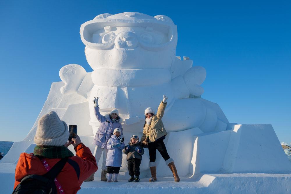 2025年1月3日，在黑龍江哈爾濱冰雪大世界園區(qū)，游客與亞冬會(huì)吉祥物雪雕“濱濱”合影