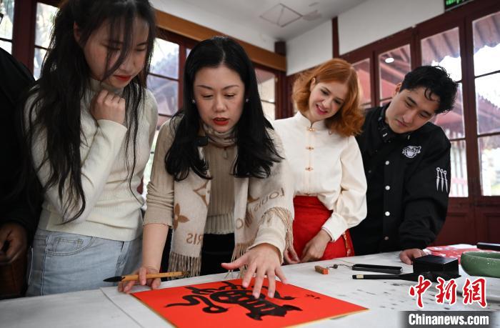 1月20日，西泠印社社員李硯（左二）為外籍留學生講述蛇年福字貼創(chuàng)作靈感。當日，來自巴西、馬來西亞、加納、哈薩克斯坦的外籍留學生在浙江杭州西泠印社體驗福貼、春聯(lián)和篆刻，感受古老的中國傳統(tǒng)文化。中新社記者 王剛 攝