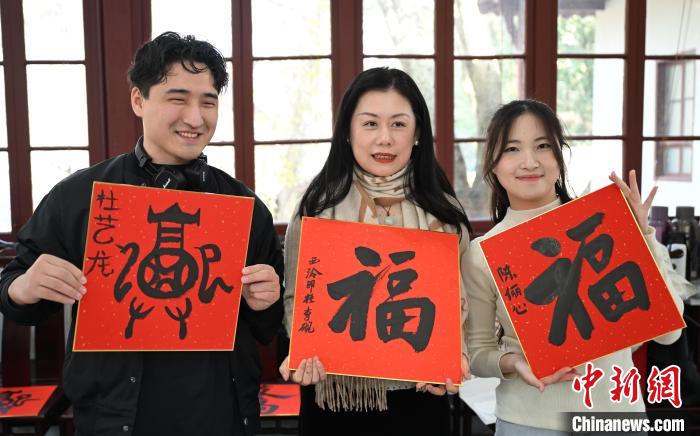 1月20日，外籍留學生和西泠印社社員李硯(中)展示各自創(chuàng)作的福貼。當日，來自巴西、馬來西亞、加納、哈薩克斯坦的外籍留學生在浙江杭州西泠印社體驗福貼、春聯(lián)和篆刻，感受古老的中國傳統(tǒng)文化。中新社記者 王剛 攝
