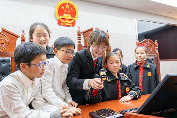 圖①：干警帶同學(xué)們體驗敲法槌。