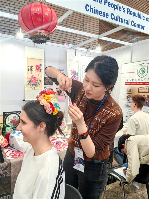 展覽正值羅馬尼亞迎春花節(jié)，國(guó)際中文教師志愿者潘婧穎向游客們介紹了國(guó)家非物質(zhì)文化遺產(chǎn)——福建泉州的簪花文化。布加勒斯特大學(xué)孔子學(xué)院供圖。