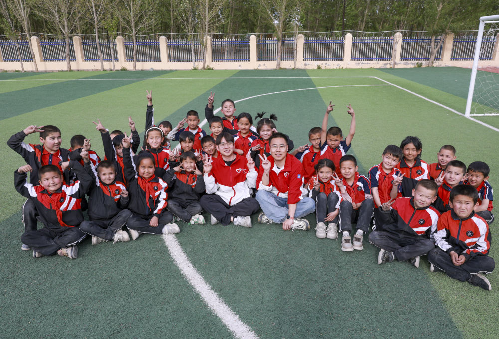 4月23日，在新疆克州阿圖什市哈拉峻鄉(xiāng)謝依特小學(xué)，支教教師王俊文（中左）、李軻凡（中右）和學(xué)生在一起。