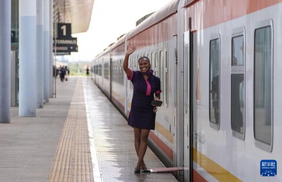 5月31日，在蒙內(nèi)鐵路內(nèi)羅畢站，一名乘務(wù)員在即將開往蒙巴薩的E2次列車旁等候乘客。新華社記者 李亞輝 攝